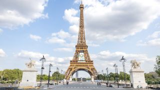 Am Eiffelturm in Paris hÃ¤ngt das Logo der Olympischen Spiele mit den Olympischen Ringen.