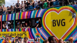 Ein mit Regenbogenfarben geschmÃ¼ckter Doppeldecker-Bus der BVG fÃ¤hrt im CSD-Demozug.