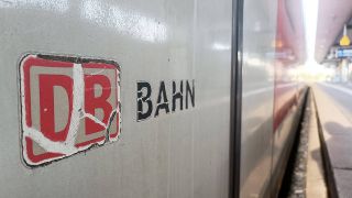 Ein verwittertes Logo der Deutschen Bahn an einem Schnellzug, der in einem Bahnhof steht.