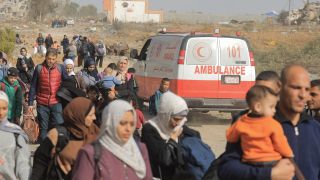 Menschen im Gazastreifen gehen an einem Krankenwagen vorbei.