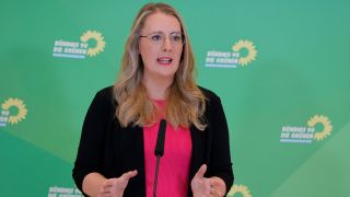 Die GrÃ¼nen-Fraktionsvorsitzende Katharina DrÃ¶ge spricht bei einer Pressekonferenz vor grÃ¼nem Hintergrund.