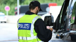 Polizist Ã¼berprÃ¼ft einen Fahrer an der deutsch-Ã¶sterreichischen Grenze (Bild: picture alliance/dpa/Revierfoto)