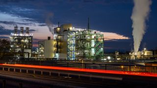 Dampf und Rauch steigen aus einer Industrieanlage im Chemiepark Wesseling im Vordergrund sind die vorbeiziehenden RÃ¼cklichter eines Autos zu sehen.