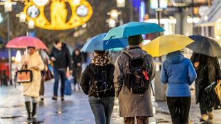 Passanten gehen mit Regenschirmen Ã¼ber eine EinkaufsstraÃe in Essen.