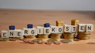 Scrabble-WÃ¼rfel bilden auf einem Stapel Euro-MÃ¼nzen das Wort Energiekosten.