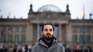 Tareq Alaows steht vor dem ReichstagsgebÃ¤ude in Berlin.