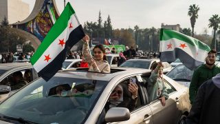 Zwei MÃ¤dchen schwenken in Damaskus syrische Fahnen aus einem Auto heraus. 