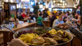 Eine Kellnerin trÃ¤gt im HofbrÃ¤u Berlin bei einem Weihnachtsessen eine Pfanne zum Tisch. 