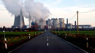 Eine StraÃe fÃ¼hrt auf das Kohlekraftwerk NiederauÃem mit seinen groÃen KÃ¼hltÃ¼rmen hin.