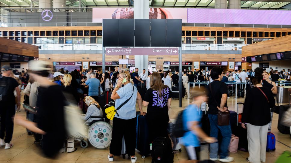 Zahlreiche Fluggäste warten am Hauptstadtflughafen BER vor einer schwarzen Anzeigetafel (Bild: picture alliance/dpa | Christoph Soeder)