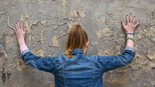Junge Frau lehnt an Wand. Symbolbild für Perspektivlosikgkeit (Quelle: imago/Photocase)