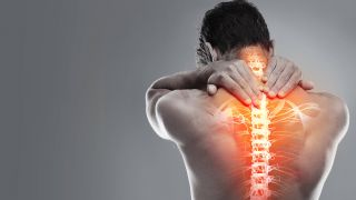 HWS-Syndrom: Mann mit Nackenschmerzen hält sich hinteren Hals an Wirbelsäule (Bild: imago images/Zoonar)