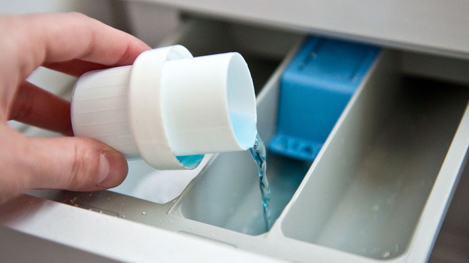 Waschmittel wird mit der Hilfe einer Messkappe in das Waschmittelfach gegeben (Quelle: picture alliance / dpa Themendienst | Andrea Warnecke)