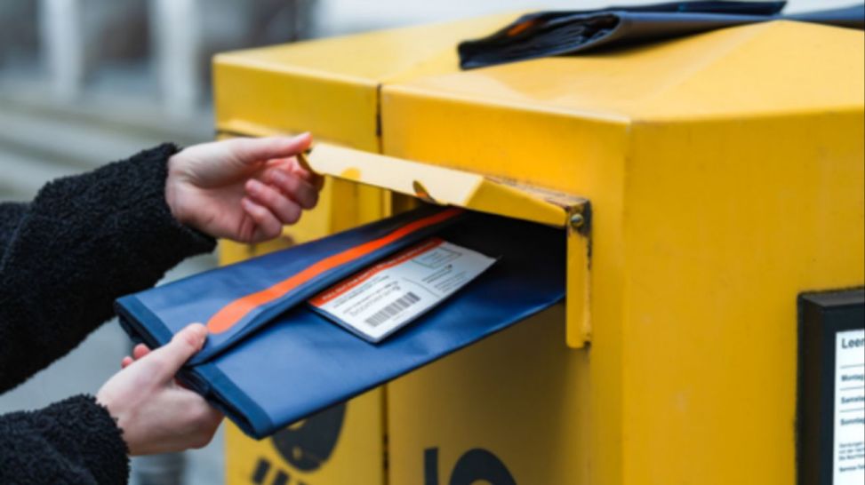 Eine Boomerang-Versandtasche wird in einen Briefkasten geworfen (Quelle: Boomerang Systems UG)