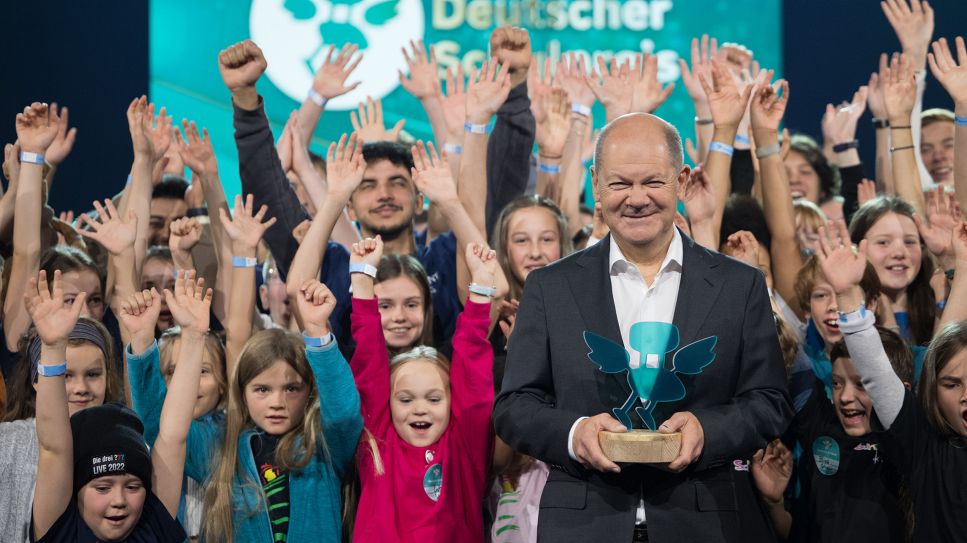 Bundeskanzler Olaf Scholz (SPD) steht am 02.10.2024 während der Verleihung des Deutschen Schulpreises 2024 im Tempodrom zwischen Schülerinnen und Schülern der Schulen, die ins Finale gekommen sind. (Quelle: dpa-Bildfunk/Sebastian Gollnow)